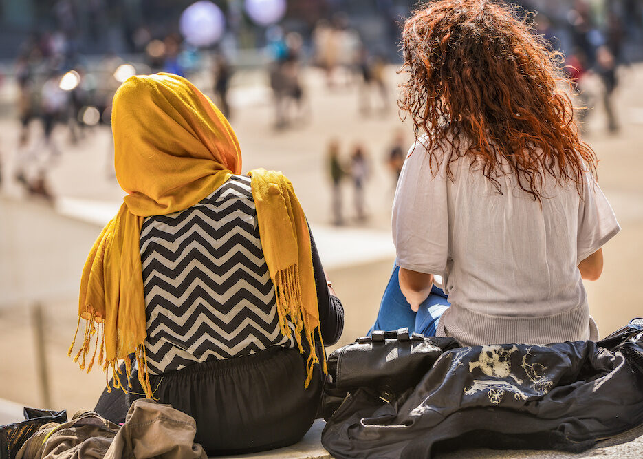 Two girls sitting and chatting outdoors